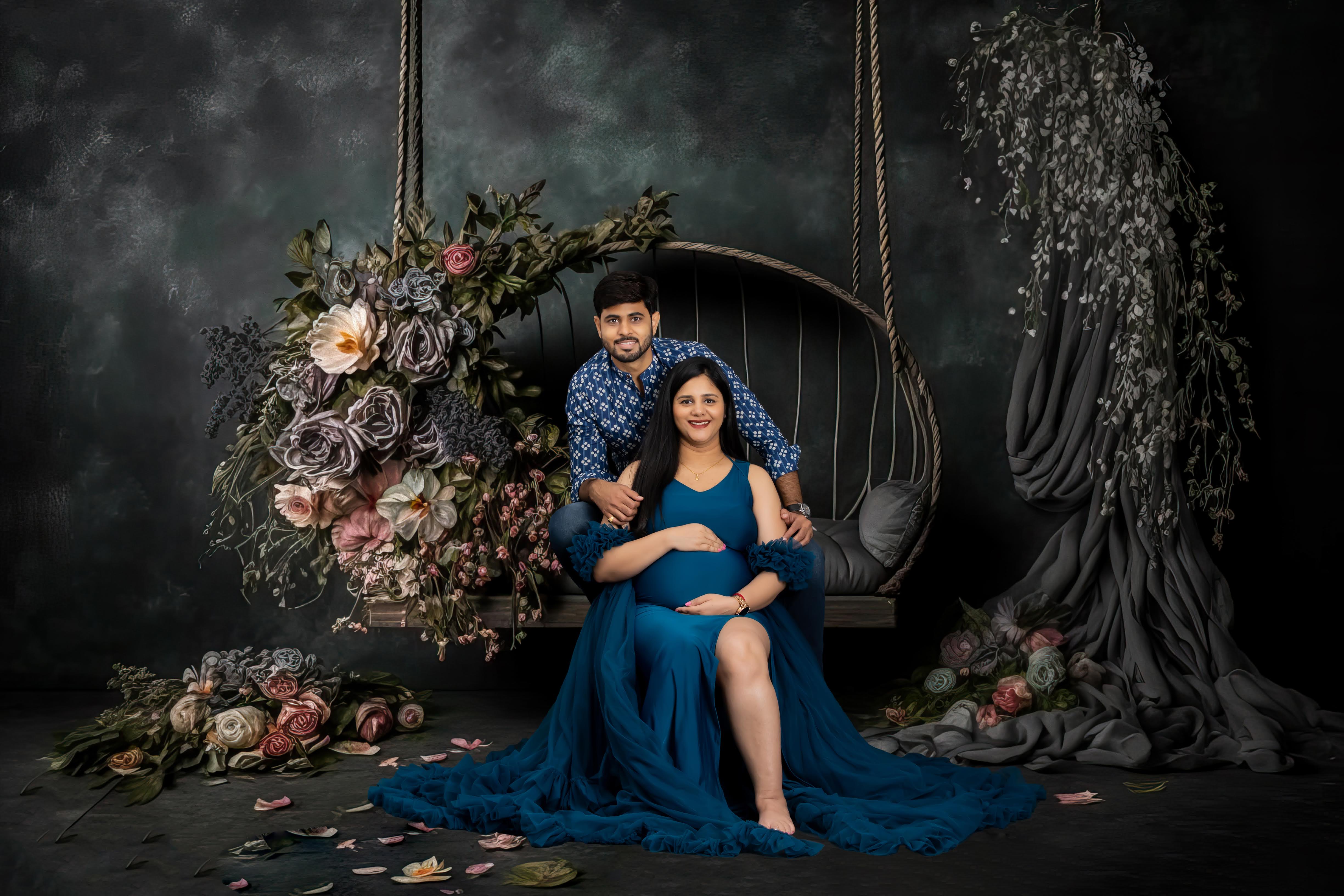 A classic maternity photoshoot featuring a beautifully dressed couple on a floral swing.